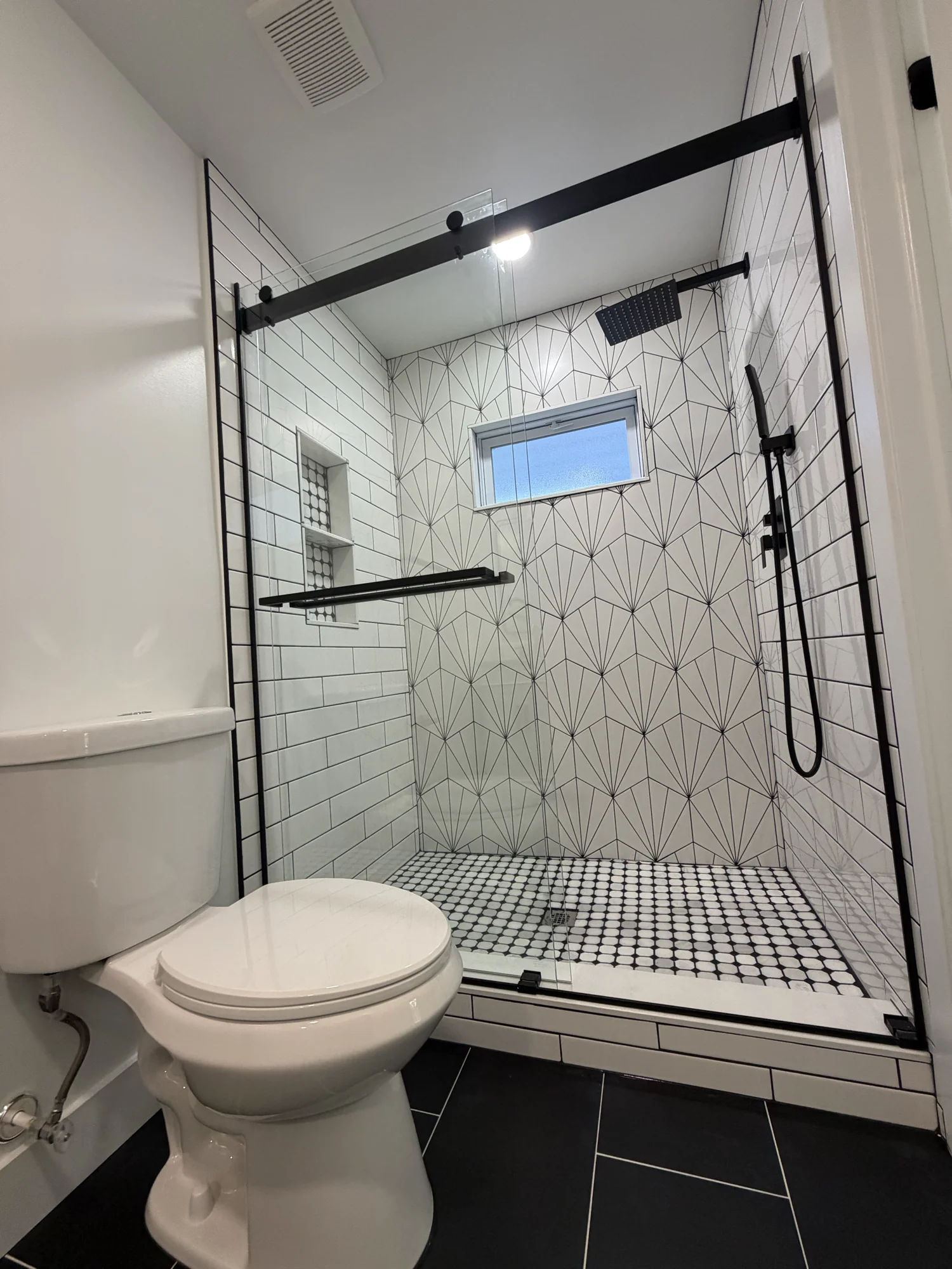 Walk-in tile shower with geometric wall tile and matte black fixtures