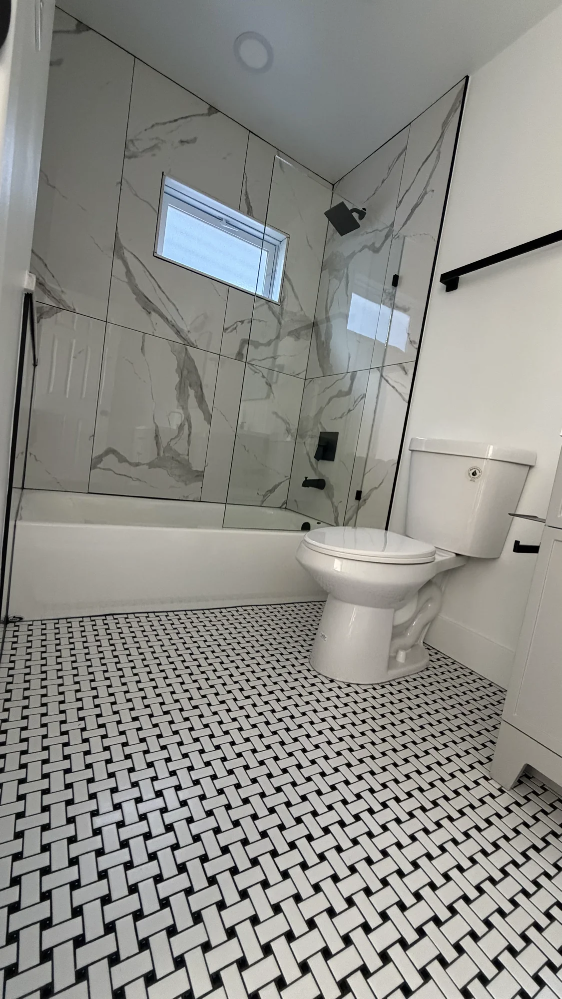 Marble-look tub surround with basketweave mosaic tile floor