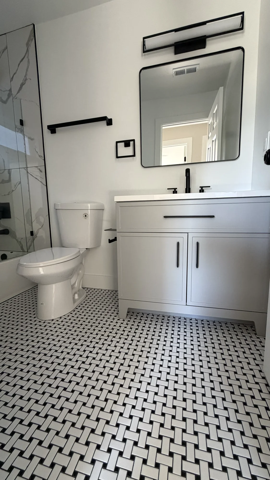 Bathroom vanity with black fixtures and basketweave tile floor